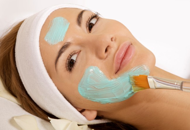 Млада жена, която получава красота кожа маска лечение на лицето си wo