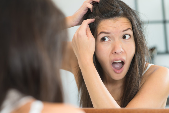 Horrified ung kvinna tittar i spegeln