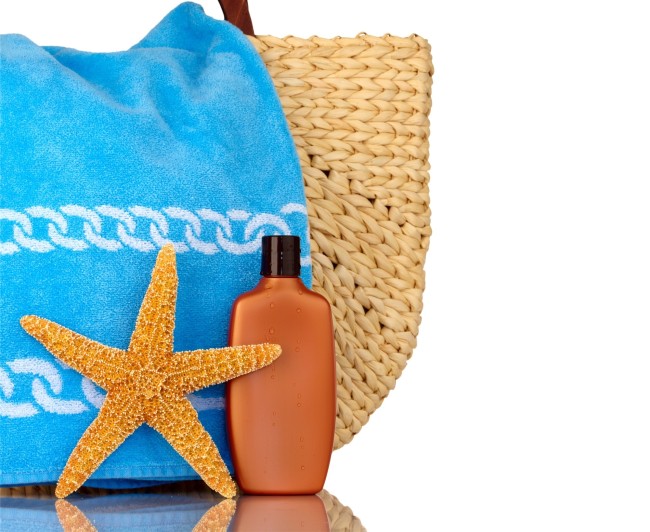 Halmstrandväska, blå handduk, solskyddsmedel, sjöstjärna isolerad på vitt