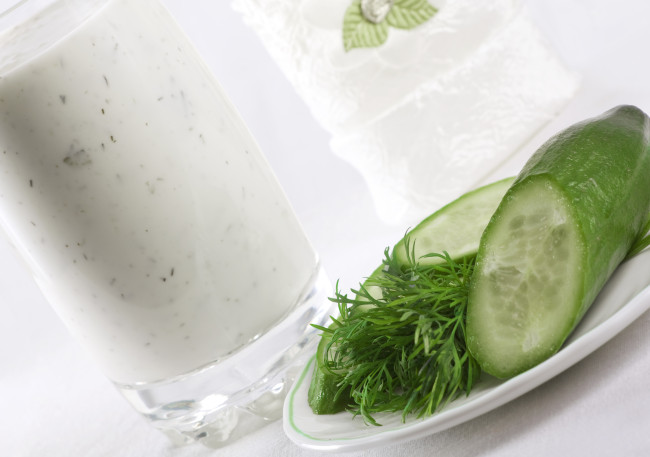 Composition of kefir in the glass with cucumber and dill near on the plate