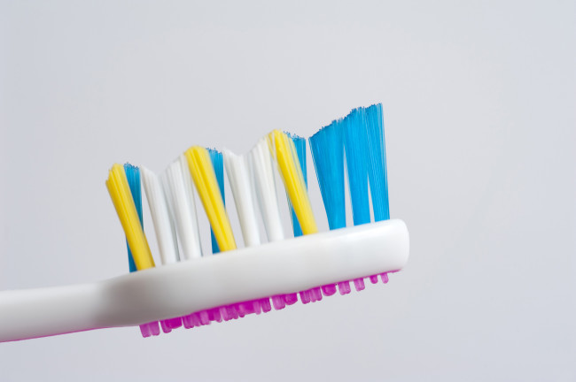 หัวแปรงสีฟันที่มีขนแปรงสีสันสดใสและเครื่องฟอกลิ้นสีชมพูเพื่อทำความสะอาดพื้นผิวของลิ้นในขณะที่แปรงฟัน