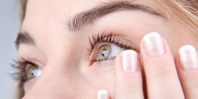 Opened green eyes and fingernails with french manicure close-up