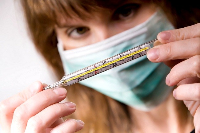 Woman with respiratory mask looking at thermometer