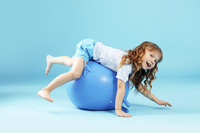 Copil cu minge gimnastică pe fundal studio Bleu