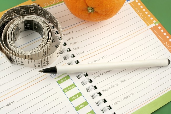 writing in a diet and nutrition journal with orange to the side