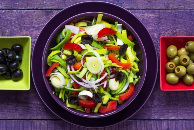 Salată de legume colorată proaspătă pe o platou și masă de lemn