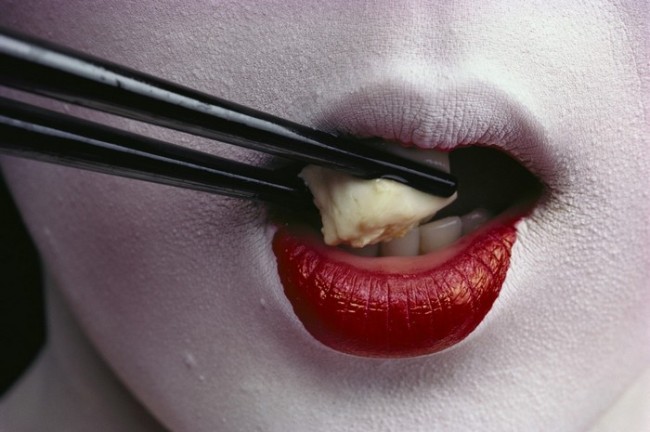 Nära syn på en geisha som äter tofu med ätpinnar.