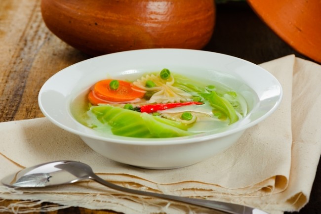 spicy cabbage soup in a white plate on a wood table