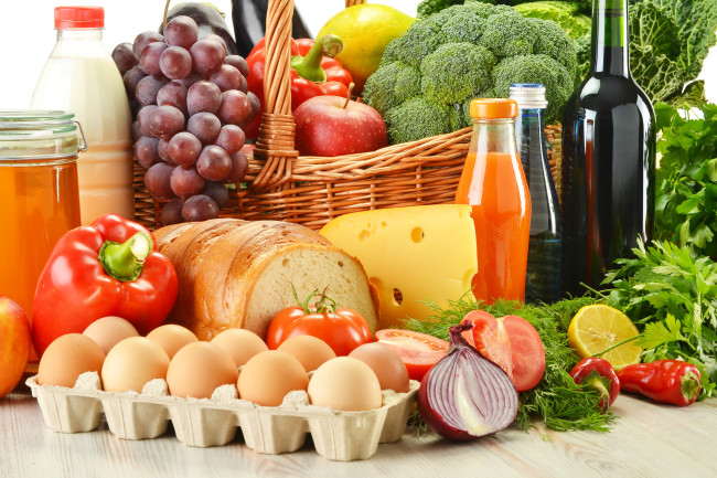 Нахваща в плетена кошница, включително зеленчуци, плодове, хлебни и млечни продукти и вино изолирани на бяло
