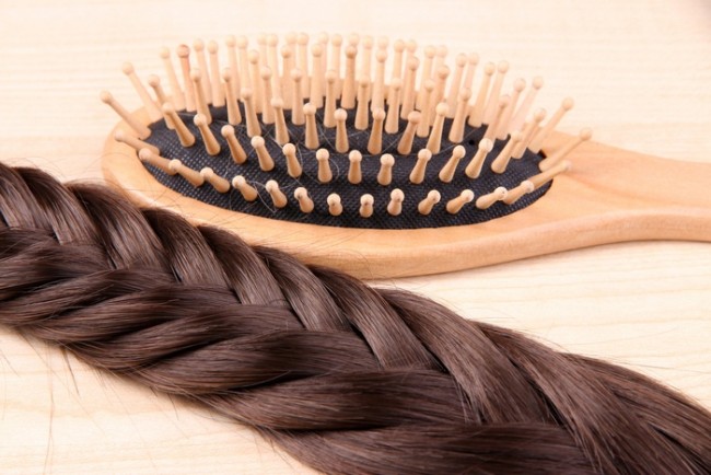 Long brown hair with hairbrush on wooden background