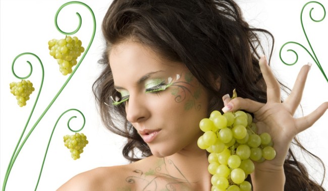 pretty girl with bodypaint on shoulder and face looking down with grape