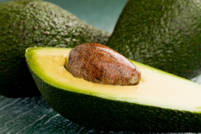 foto de fruta de abacate cortada na mesa de vidro verde