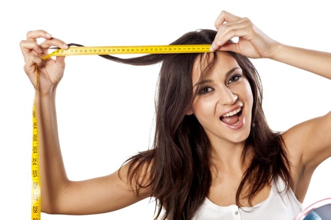 Happy attractive girl measured her hair with a tape measure